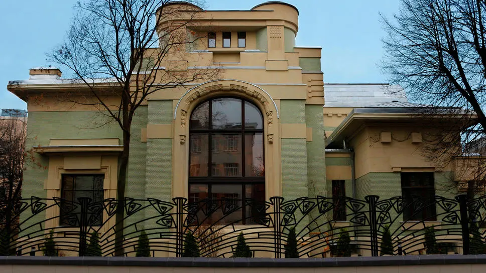 Главный фасад дома за кованым забором в стиле модерн